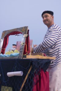 Thierry Rousse conte des histoires au bord de la mer avec des figurines et des planches illustrées. Pêcheurs d'histoires, conte et théâtre d'objets "Le Grain de sable et la Perle magique"